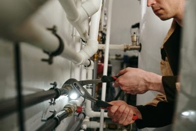 Technician inspecting commercial plumbing pipes in Baldwin Park