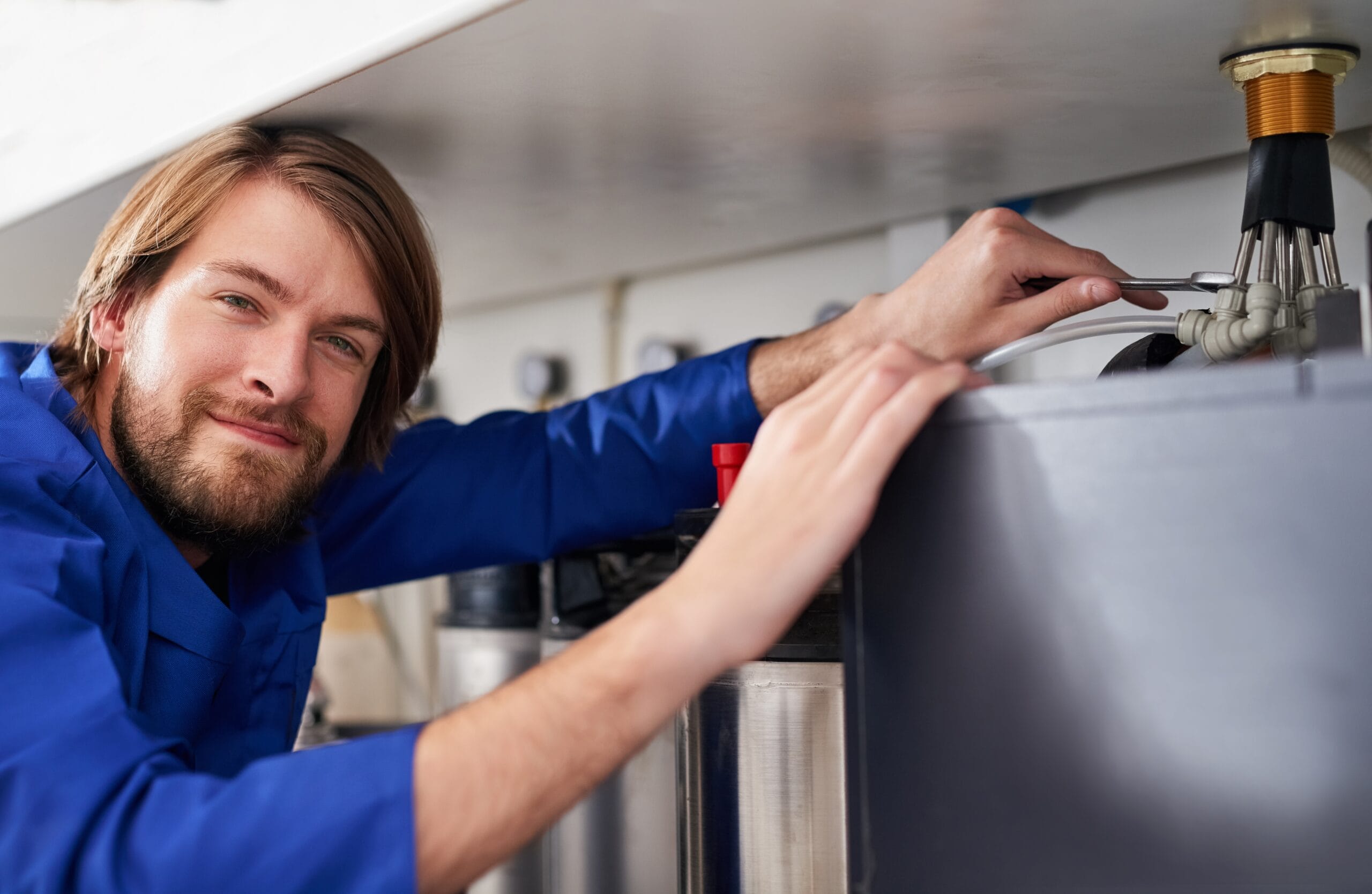 Technician servicing a residential water heater tank in Baldwin Park